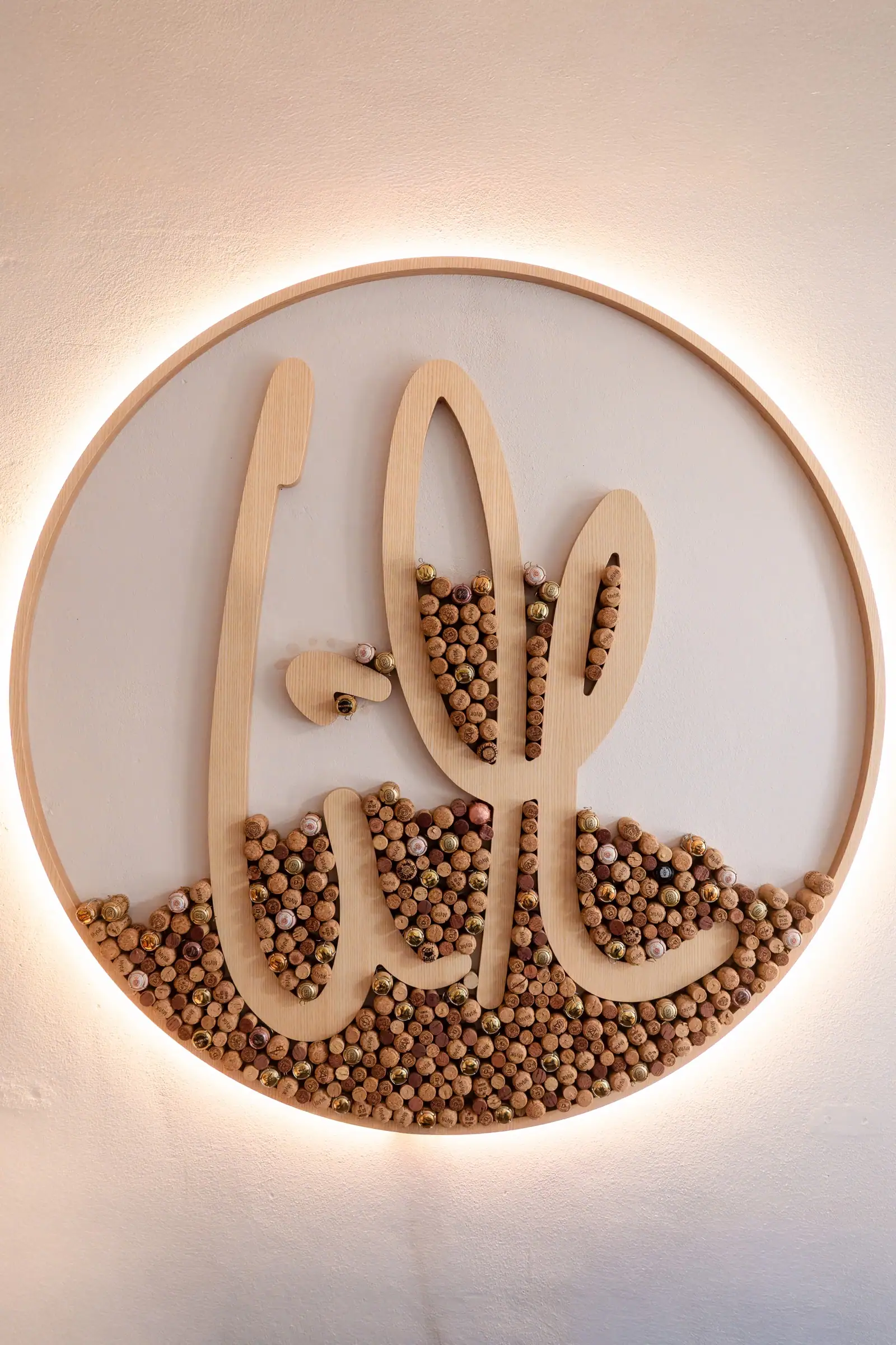 The LM monogram on the wall, half filled with corks
