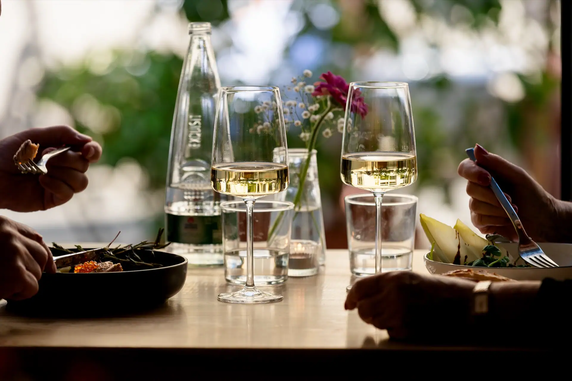 Two glasses of white wine, guests dining